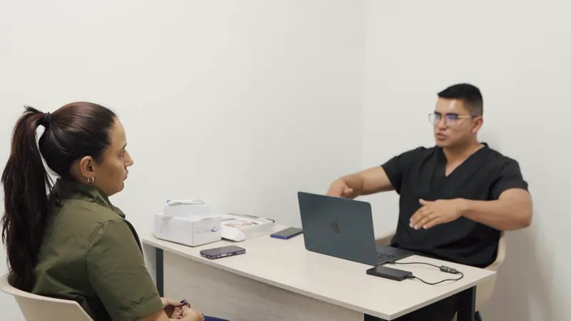 El profesional de QuiroFit conversa y explica su orientación a una mujer en el consultorio
