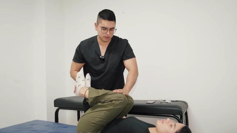El profesional guía un movimiento de piernas de una mujer recostada