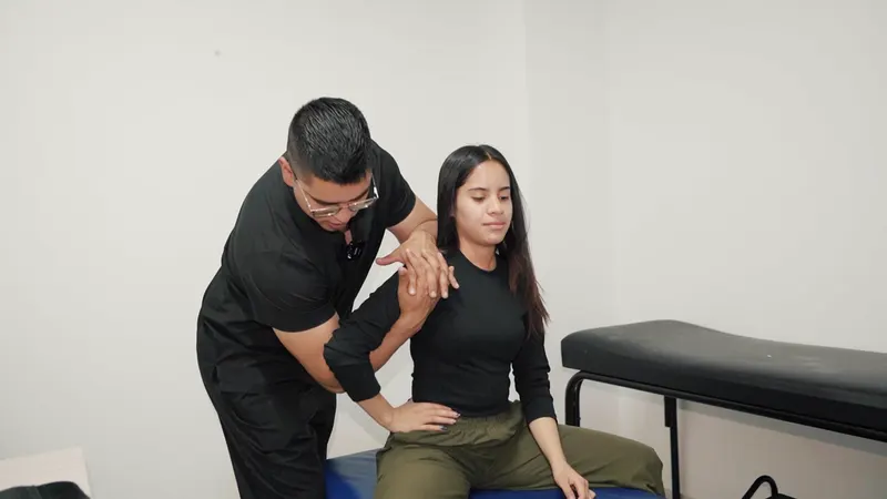 El profesional de QuiroFit acompaña un movimiento del brazo y hombro de una mujer sentada