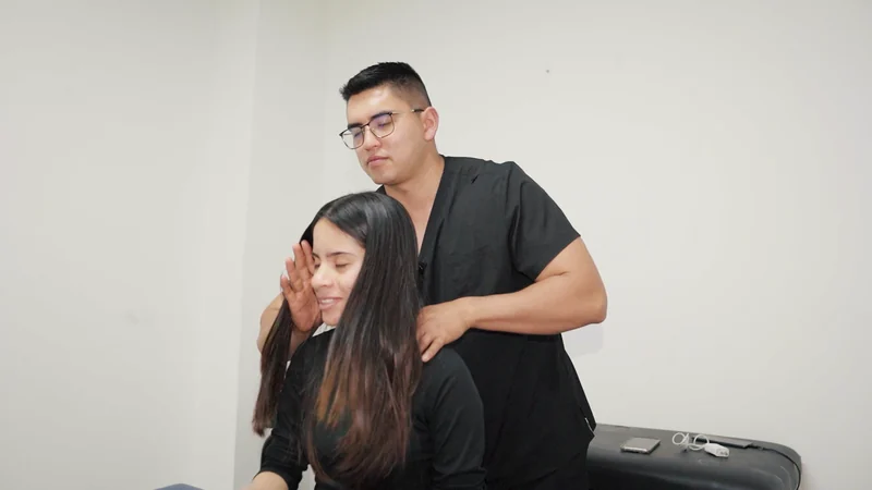 El profesional acompaña el movimiento del cuello de una mujer sentada